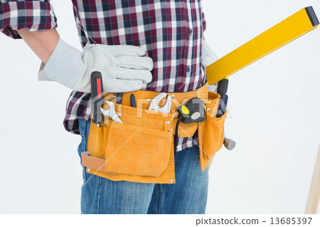 Repairman wearing tool belt while standing with hands on hips Repairman wearing tool belt while standing with hands on hips 13685397