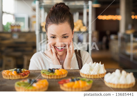 Pretty brunette looking at tarts Pretty brunette looking at tarts 13685441