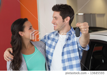 Smiling couple holding their new car key Smiling couple holding their new car key 13685593