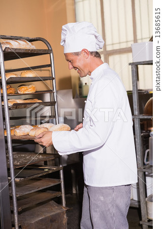 Smiling baker holding tray of bread 13685615
