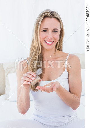 Smiling blonde taking her pills Smiling blonde taking her pills 13685694