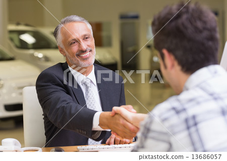 Smiling salesman shaking a customer hand Smiling salesman shaking a customer hand 13686057