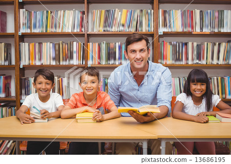 Cute pupils and teacher looking at camera in library Cute pupils and teacher looking at camera in library 13686195