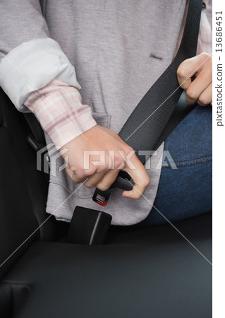 Woman putting on her seat belt Woman putting on her seat belt 13686451