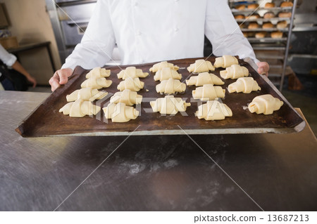 Close up of baker holding tray of raw dough 13687213