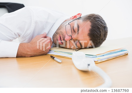 Exhausted businessman sleeping at his desk 13687760