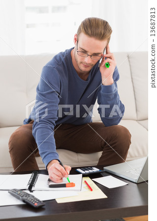 Concentrated man with glasses taking notes Concentrated man with glasses taking notes 13687813