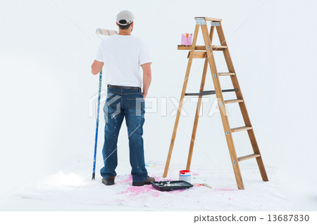 Man with paint roller standing by ladder Man with paint roller standing by ladder 13687830