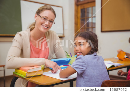 Pretty teacher helping pupil in classroom Pretty teacher helping pupil in classroom 13687952