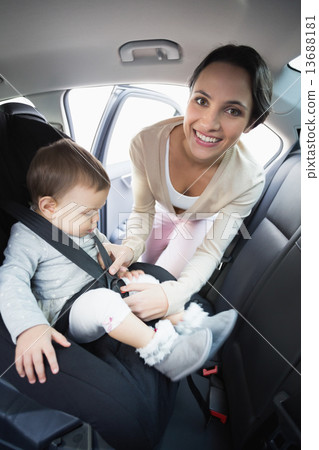 Mother securing her baby in the car seat 13688181