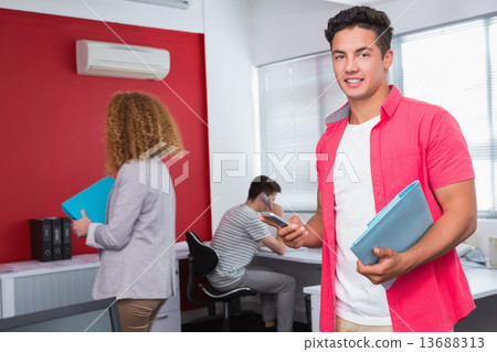 Smiling student using smartphone near classmates Smiling student using smartphone near classmates 13688313