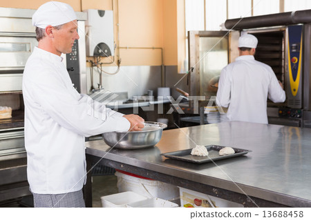 Baker making dough in mixing bowl 13688458