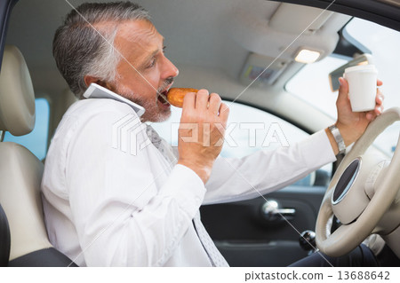 Man drinking coffee and eating donnut on phone 13688642