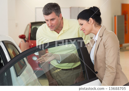 Businesswoman showing a car interior to her customers Businesswoman showing a car interior to her customers 13688705