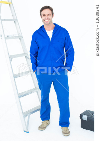 Carpenter in overalls standing with hands in pockets 13689241
