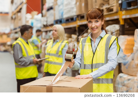 Smiling warehouse workers preparing a shipment Smiling warehouse workers preparing a shipment 13690208