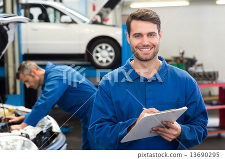 Smiling mechanic writing on clipboard Smiling mechanic writing on clipboard 13690295