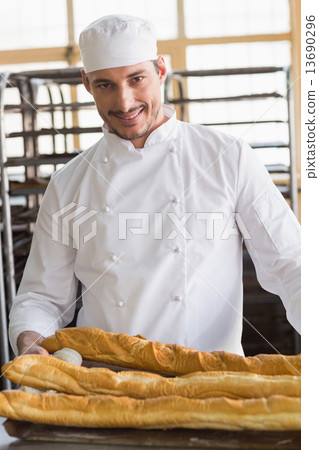 Baker looking at freshly baked baguettes 13690296
