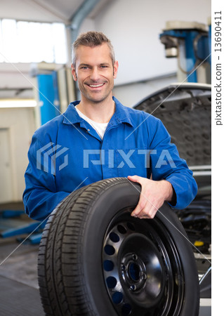 Mechanic holding a tire wheel Mechanic holding a tire wheel 13690411