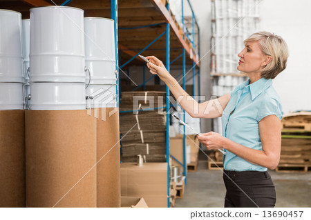 Warehouse manager checking her list on clipboard Warehouse manager checking her list on clipboard 13690457