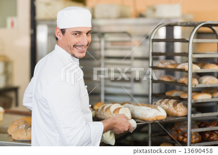 Smiling baker holding tray of bread Smiling baker holding tray of bread 13690458