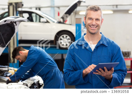 Stock Photo: Smiling mechanic using a tablet pc