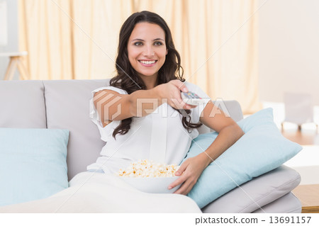 Pretty brunette watching tv on couch 13691157