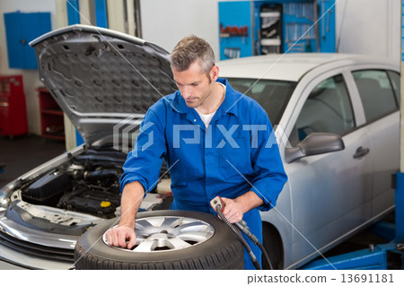 Focused mechanic inflating the tire Focused mechanic inflating the tire 13691181