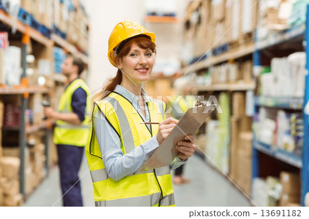 Smiling warehouse manager holding clipboard 13691182
