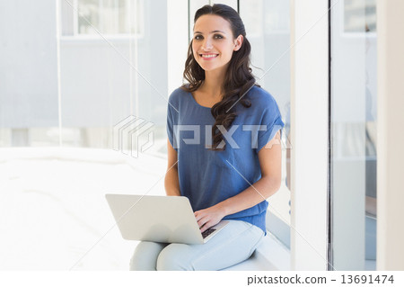 Pretty brunette using her laptop Pretty brunette using her laptop 13691474