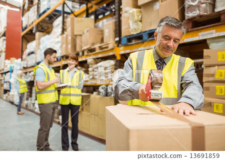 Warehouse worker sealing cardboard boxes for shipping Warehouse worker sealing cardboard boxes for shipping 13691859