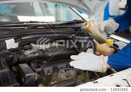Mechanic pouring oil into car Mechanic pouring oil into car 13691860