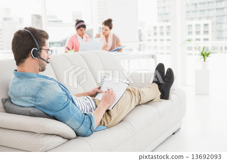 Businessman with headset phoning and taking notes Businessman with headset phoning and taking notes 13692093