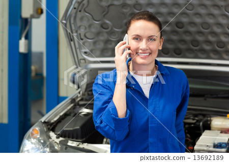Mechanic smiling at the camera on the phone 13692189