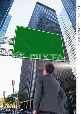 Composite image of businessman standing with hand on hip 13692318