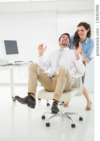 Smiling partners playing together with swivel chair Smiling partners playing together with swivel chair 13692906
