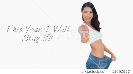 Victorious woman holding her too big pants thumbs up 13692907