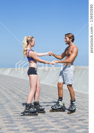 Fit couple rollerblading together on the promenade Fit couple rollerblading together on the promenade 13693890