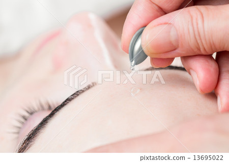 Serum capsule facial treatment of young woman in spa salon 13695022