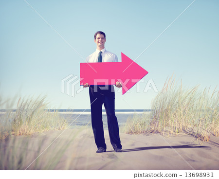 Businessman holding arrow on beach 13698931