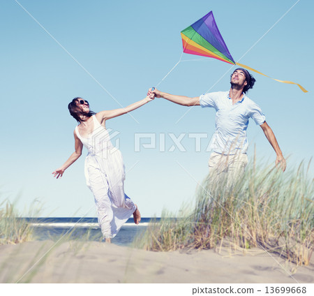 Cheerful Couple Playing Kite by the Beach 13699668
