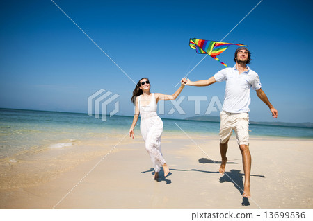 A couple flying a kite on the beach A couple flying a kite on the beach 13699836