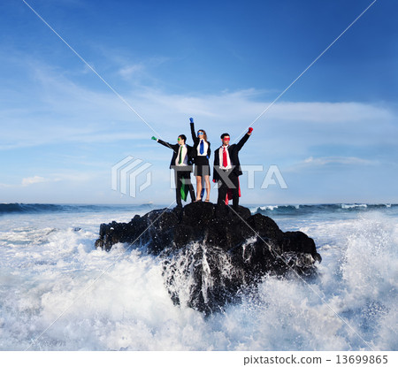 Three Business People Wearing Superhero Costumes Posing On A Roc 13699865