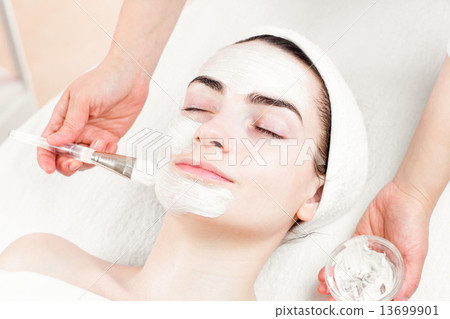 Young woman facial mask applying in beauty parlour 13699901