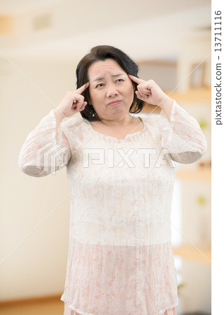 A middle-aged woman in casual wear suffering from low back pain, stiff shoulder standing in the room 13711116