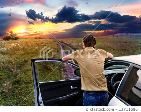 guy is standing near car and looking at the sunset 13711686
