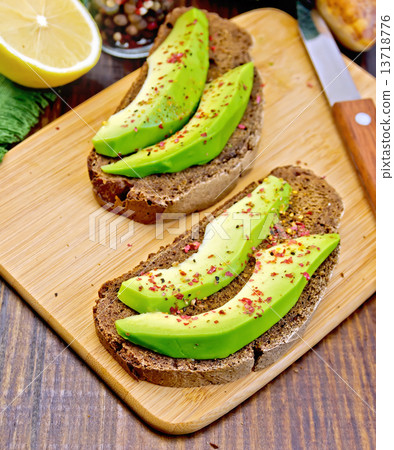 Sandwich with avocado and lemon on board 13718776