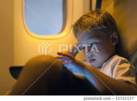 Little boy using tablet computer during flight Little boy using tablet computer during flight 13722137