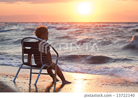 Little child looking at sunset sitting by the sea 13722140