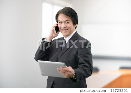 一個穿著西裝站在公司會議室裡的中年男子 13725201
